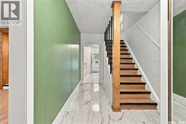 Interior view of a room with white walls, a patterned floor, and wooden railings. - 420 J Avenue N, Saskatoon