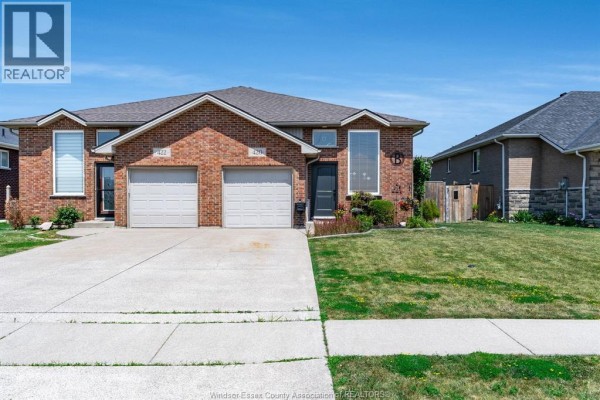 Front exterior view of a brick duplex with two garage doors and concrete driveway. - 420 Marla Crescent, Lakeshore