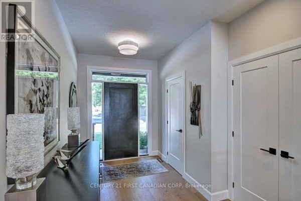 Interior hallway with light grey walls, hardwood floors, and a dark front door. - 420 Old Wonderland Road, London South