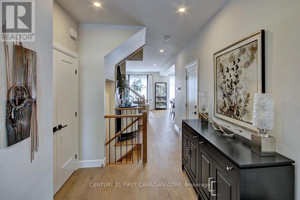 Wide interior hallway with light grey walls, hardwood floors, and a staircase on the left. - 420 Old Wonderland Road, London South