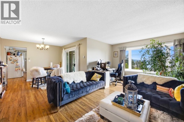 Living room with two navy blue sofas, a white ottoman coffee table, and a dining area in the background. - 420 Strang Dr, Ladysmith
