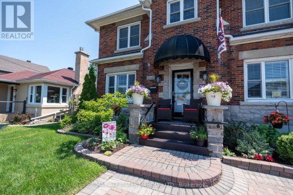 Close-up of the front entrance with a black awning, stone steps, and potted plants. - 420 Third Street W, Cornwall