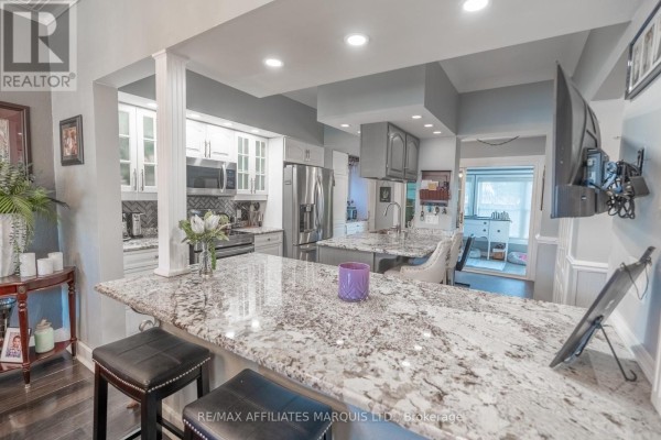Formal dining room with a glass table, patterned chairs, red rug, and chandelier. - 420 Third Street W, Cornwall