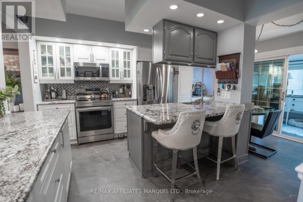 Dining room with a view of the kitchen island, bar stools, and a large crystal chandelier. - 420 Third Street W, Cornwall