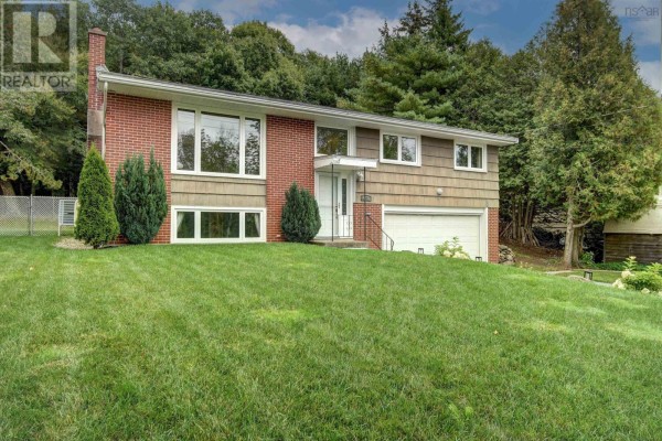 View of the front exterior of a split-level house featuring red brick and shingle siding, and a two-car garage. - 4200 Highway 2, Wellington