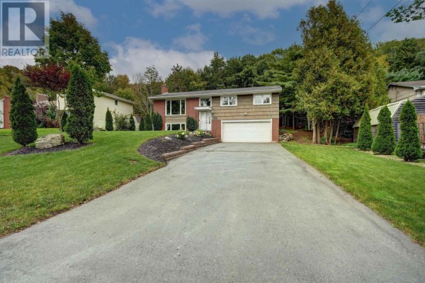 Long driveway leading to the front entrance of a split-level house with red brick and wood siding. - 4200 Highway 2, Wellington