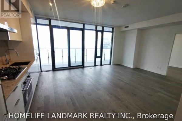 Open concept living area with grey wood floors, modern kitchen, and floor-to-ceiling windows. - 4201 - 20 Lombard Street, Toronto