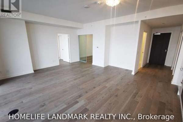 Spacious living area with grey wood floors and doorways leading to other rooms and hallway. - 4201 - 20 Lombard Street, Toronto
