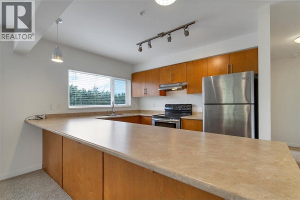 Kitchen with light wood cabinets, stainless steel appliances, and beige countertop. - 4205 27 Street Unit# 206, Vernon