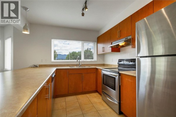 Kitchen with light wood cabinets, stainless steel appliances, and a large window. - 4205 27 Street Unit# 206, Vernon