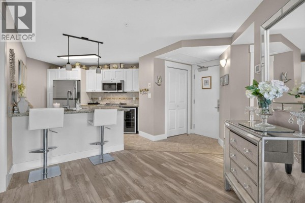 Kitchen island with bar stools, granite countertop, and white cabinetry. - 4205 Gellatly Road Unit# 336, West Kelowna