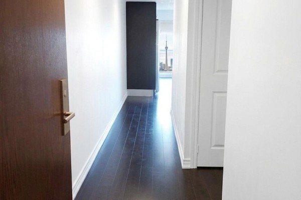 Interior hallway with dark hardwood floors, white walls, and a view of the Toronto skyline. - 4206 - 386 Yonge Street, Toronto