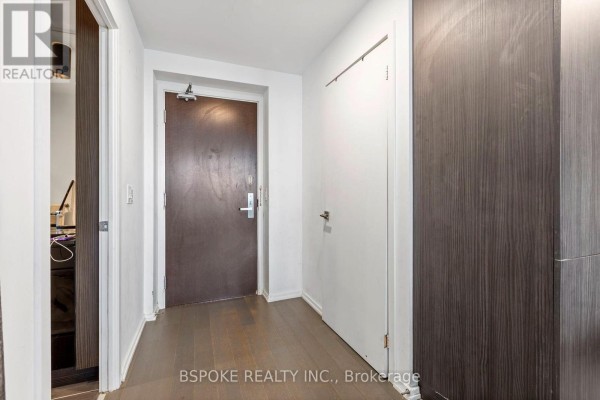 Apartment hallway with dark wood floors, a dark brown door, and white doors. - 4207 - 70 Temperance Street, Toronto