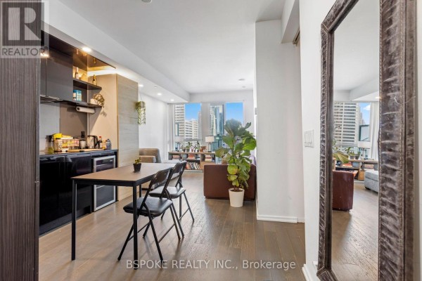 Open concept living and dining area with a small table, chairs, kitchen counter, and city views. - 4207 - 70 Temperance Street, Toronto