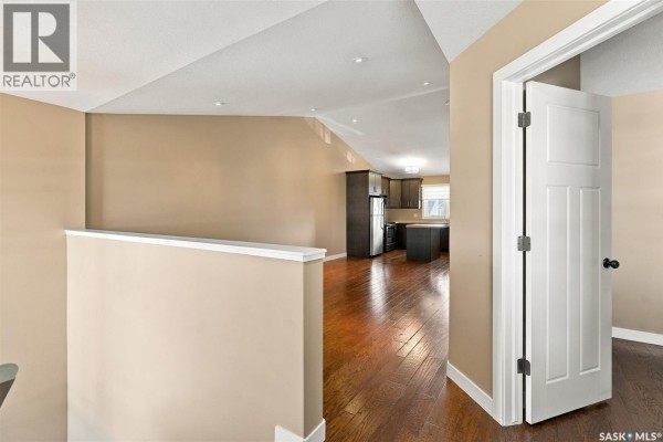 Interior staircase with beige walls, grey carpeted stairs, and white banisters. - 4207 Green Apple Drive E, Regina