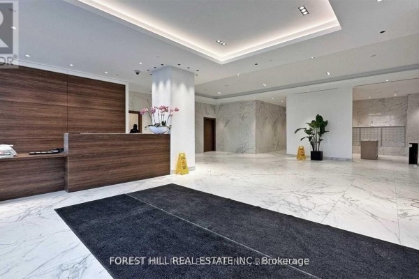 A modern lobby with marble floors, wood accents, and a reception desk. - 4208 - 1928 Lake Shore Boulevard W, Toronto