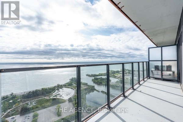 Balcony with glass railing overlooking a body of water and parkland. - 4208 - 20 Shore Breeze Drive, Toronto