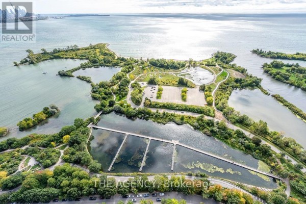 Aerial view of a green park with ponds, waterways, and distant city skyline. - 4208 - 20 Shore Breeze Drive, Toronto