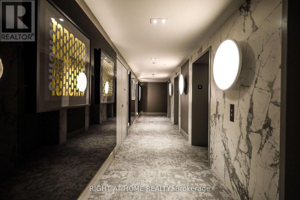 Apartment building hallway with marble-patterned walls, elevator doors, and abstract art on the left. - 421 - 285 Dufferin Street, Toronto
