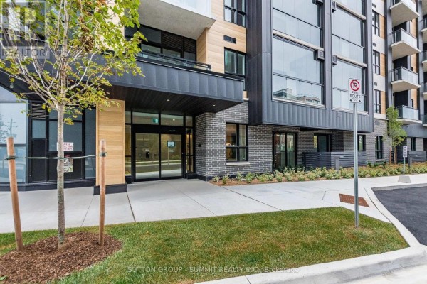 Building entrance with glass doors, brick accents, and landscaping. - 421 - 3008 William Cutmore Boulevard, Oakville