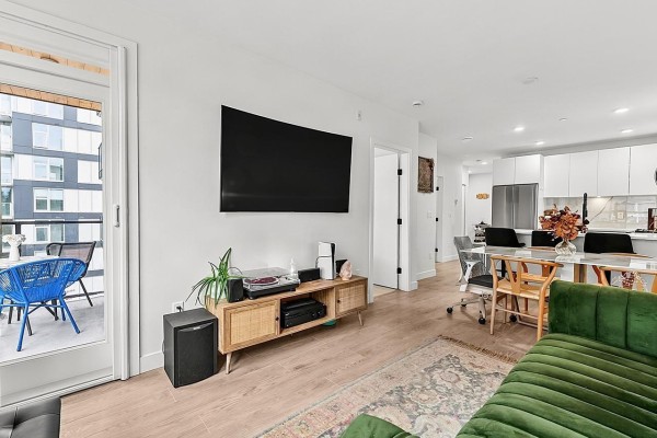 Living room with television, media console, and view of dining area and balcony. - 421 13238 105 Avenue, Surrey