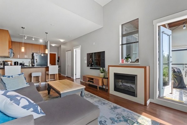 Open living space with kitchen view, fireplace, and access to balcony - 421 15918 26 Avenue, Surrey