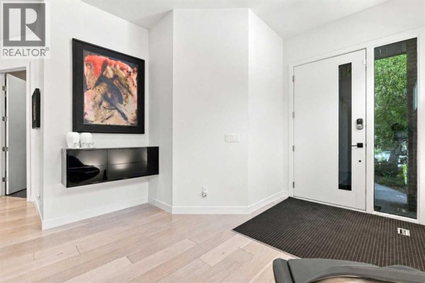 Entrance hallway with white walls, hardwood floors, and modern art. - 421 29 Avenue Ne, Calgary