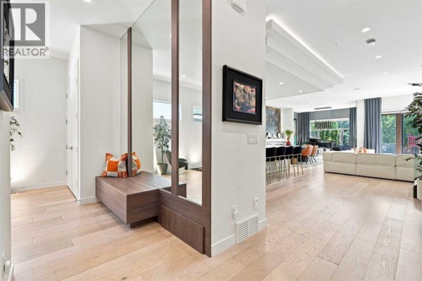Entryway with built-in bench, mirrored wall, and view into living area. - 421 29 Avenue Ne, Calgary