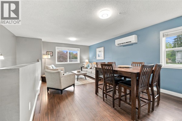 Living and dining area with a wooden dining table and chairs, and a grey sofa. - 421 Murray St, Nanaimo