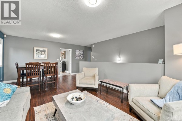Living area with two sofas, armchairs, a coffee table, and a low wall. - 421 Murray St, Nanaimo