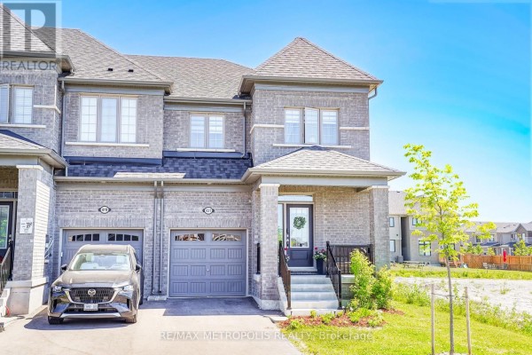 Exterior front view of a grey brick townhouse with a single car garage and covered front porch. - 421 Trevor Street, Cobourg