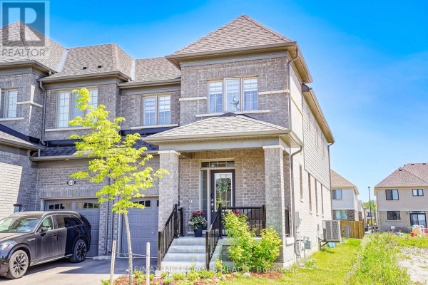 Side exterior view of a grey brick townhouse showing multiple levels and windows. - 421 Trevor Street, Cobourg