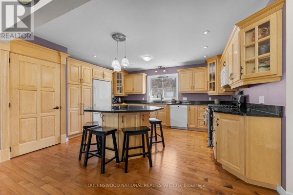 Kitchen with wood cabinets, granite counters, island, and hardwood floors - 42125 Combermere Road Ne, Madawaska Valley