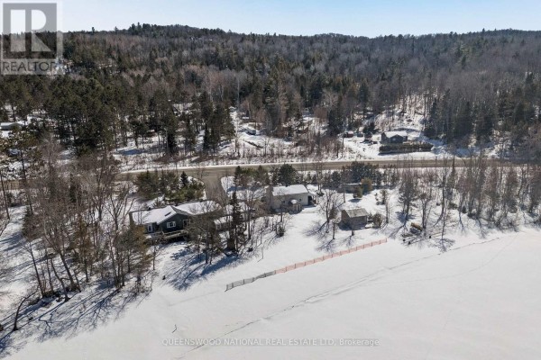 Aerial view of snow-covered property with multiple homes, a road, and dense trees - 42125 Combermere Road Ne, Madawaska Valley