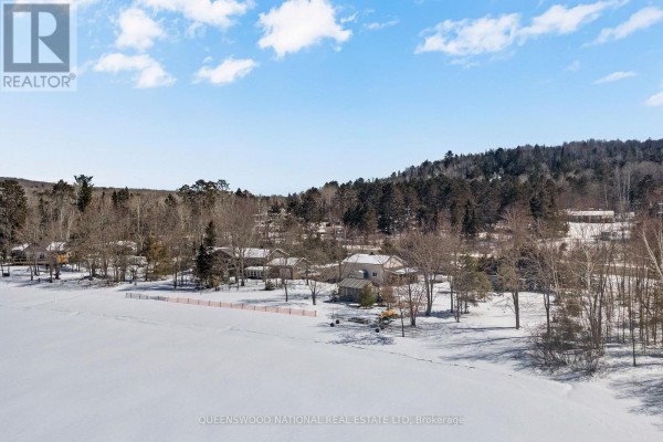 Aerial view of snow-covered houses, bare trees, and a frozen lake - 42125 Combermere Road Ne, Madawaska Valley