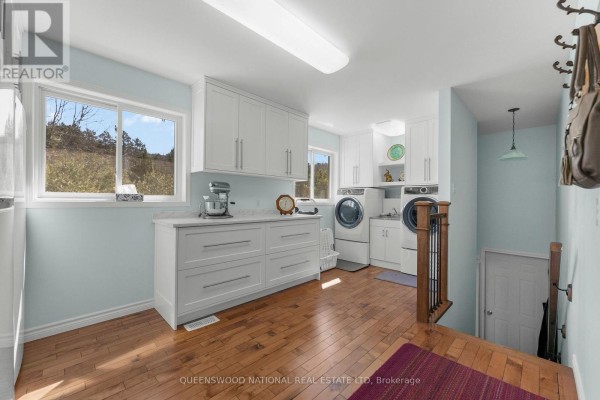 Renovated laundry room with washer, dryer, utility sink, white cabinets, hardwood floors - 42125 Combermere Road Ne, Madawaska Valley
