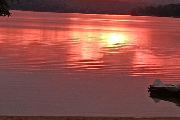 Sunset over lake with mountains, sandy shore, and boat - 42125 Combermere Road Ne, Madawaska Valley