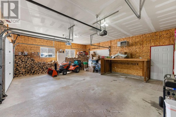 Garage with open overhead door, concrete floor, workbench, windows - 42125 Combermere Road Ne, Madawaska Valley