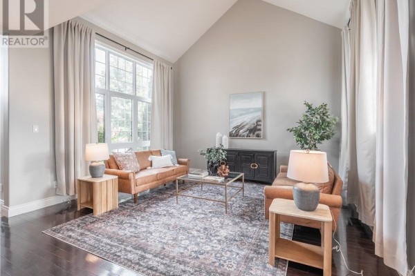 Living room with two tan sofas, vaulted ceiling, large window, and dark wood floor. - 4215 Heritage Drive, Hanmer