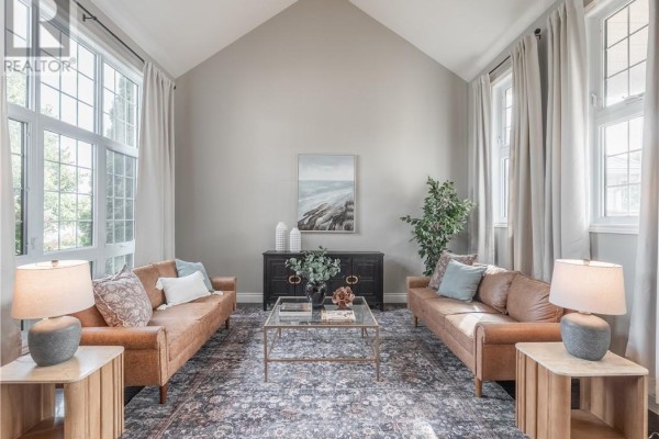 Spacious living room with vaulted ceiling, two tan sofas, and large windows on two walls. - 4215 Heritage Drive, Hanmer