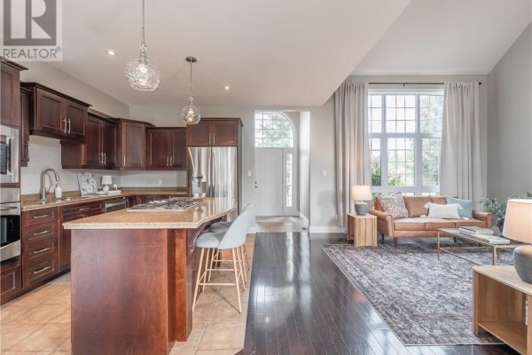Modern kitchen with dark wood cabinets, granite island, stainless steel appliances, and view to living room. - 4215 Heritage Drive, Hanmer