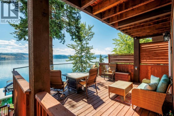 Covered deck with patio furniture and a fire table overlooking a lake. - 4215 Westside Road Unit# 10, Kelowna