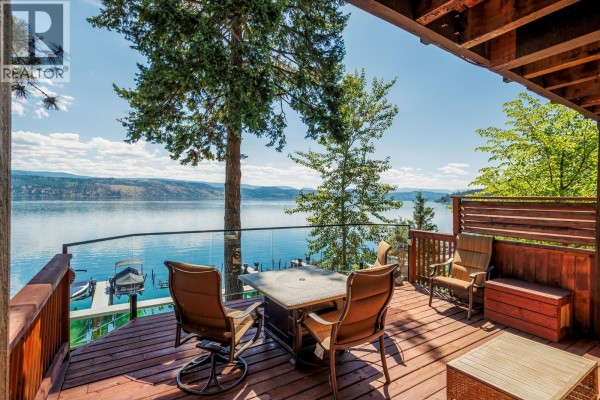 Outdoor deck with seating, fire table, and a view of a wide blue lake. - 4215 Westside Road Unit# 10, Kelowna
