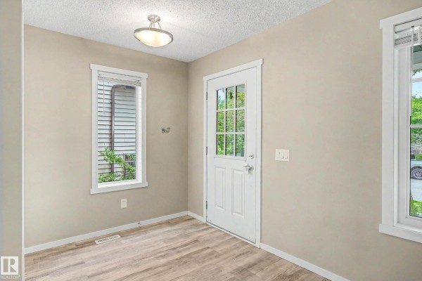 Interior entryway with a white door featuring glass panes and two windows. - 4218 Allan Li Sw, Edmonton
