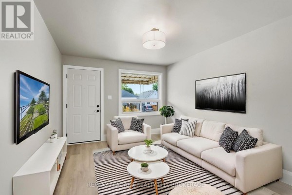Living room with a sectional sofa, armchair, two coffee tables, and a TV. - 422 Brunswick Street, Hamilton