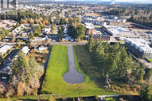 Aerial view of a modern house on a cul-de-sac street surrounded by green grass and trees. - 422 Hummingbird Pl, Parksville