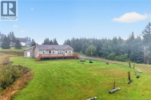 Rear view of the ranch-style house with a large wooden deck overlooking a green lawn. - 422 Indian Mountain Road, Stilesville