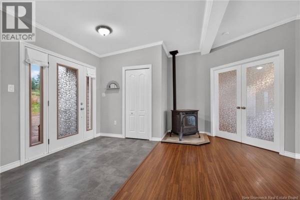 Living area with grey walls, a cast-iron wood stove on a hearth, and glass-paneled doors. - 422 Indian Mountain Road, Stilesville
