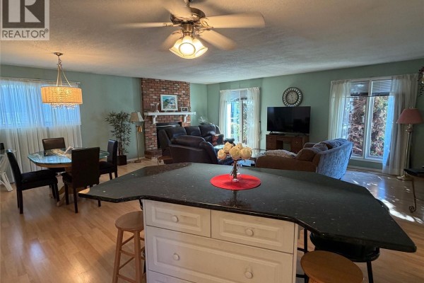 Open concept living and dining area with a large island with granite countertop and bar stools. - 422 Manning Lane, Saskatoon