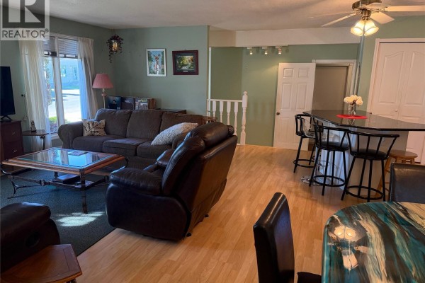 Living room with a sectional sofa, fireplace, and a view of the kitchen island and dining area. - 422 Manning Lane, Saskatoon